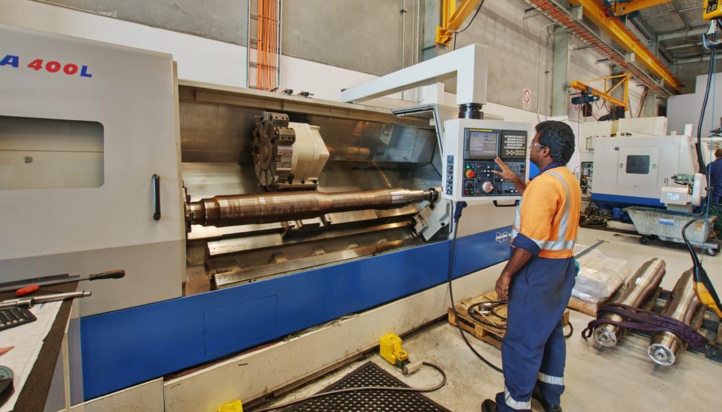 A man wearing PPE operating a CNC Machine