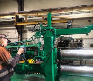 a worker inspecting an arbor slitter machine